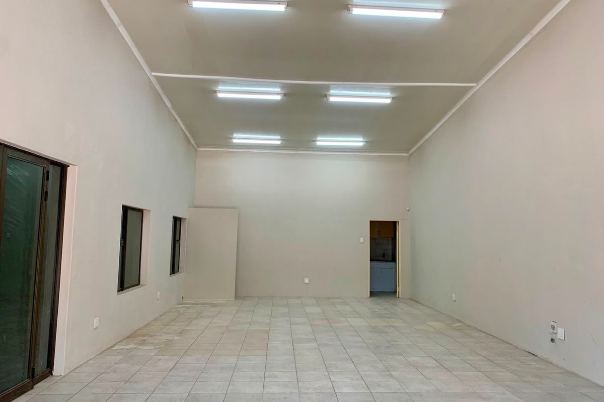 A spacious, empty office area featuring neutral walls, tiled flooring, and overhead fluorescent lighting, providing a versatile blank canvas for professional use.