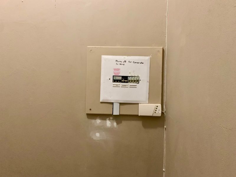 A wall-mounted electrical distribution board with circuit breakers and manual generator switching instructions.