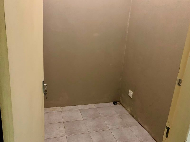 A small, empty utility space featuring ceramic floor tiles and a neutral wall finish, suitable for storage or a compact office workstation.