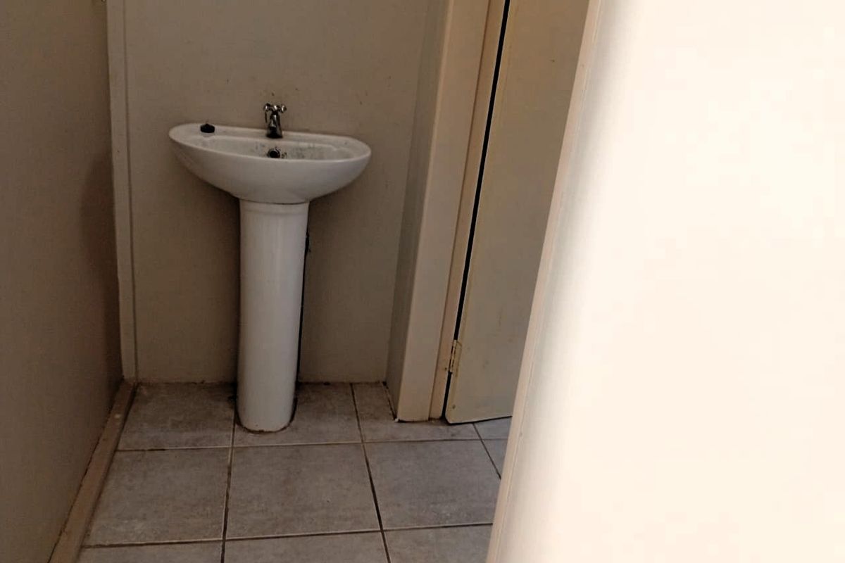 A small, functional bathroom space featuring a pedestal basin and tiled flooring, currently in need of cosmetic updates and maintenance.