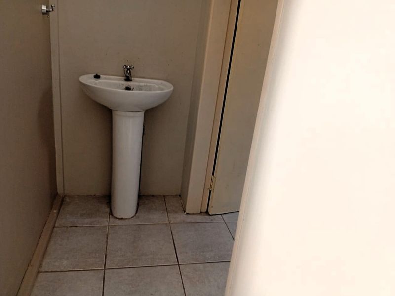 A small, functional bathroom space featuring a pedestal basin and tiled flooring, currently in need of cosmetic updates and maintenance.