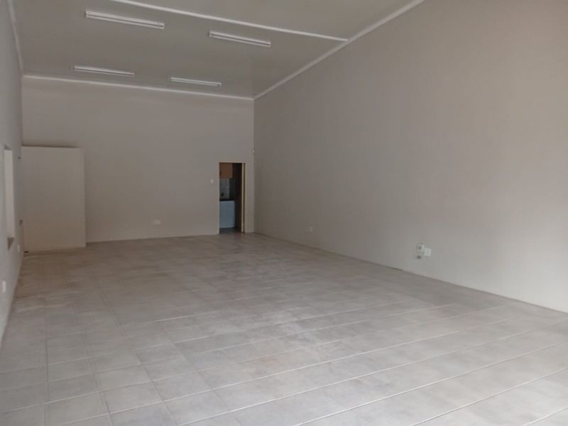 A spacious, empty office area featuring neutral wall finishes, ceramic floor tiling, and integrated fluorescent lighting, suitable for a variety of professional business configurations.
