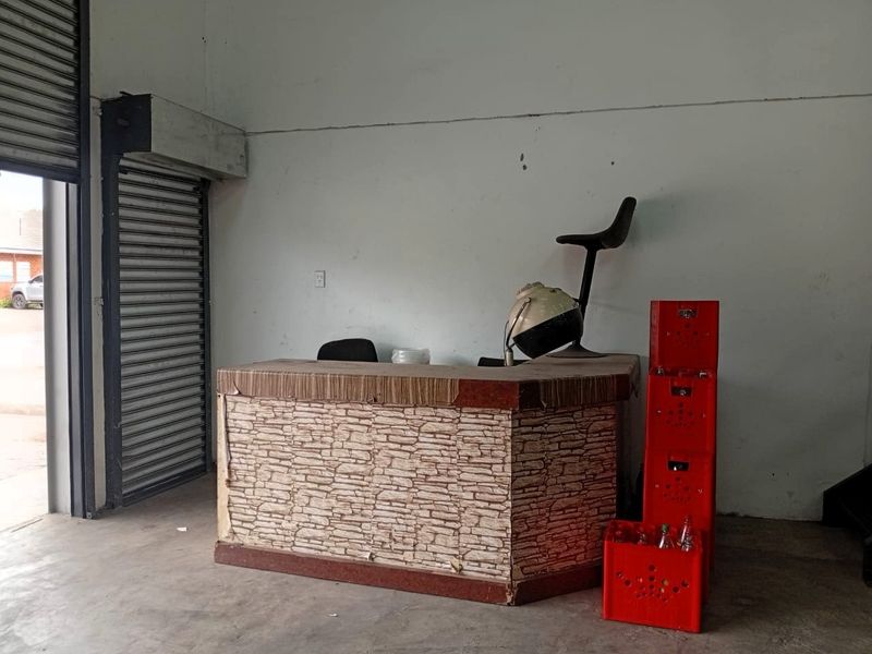 Industrial entry space featuring a concrete floor and a secure roller shutter door, suitable for a reception or service area.