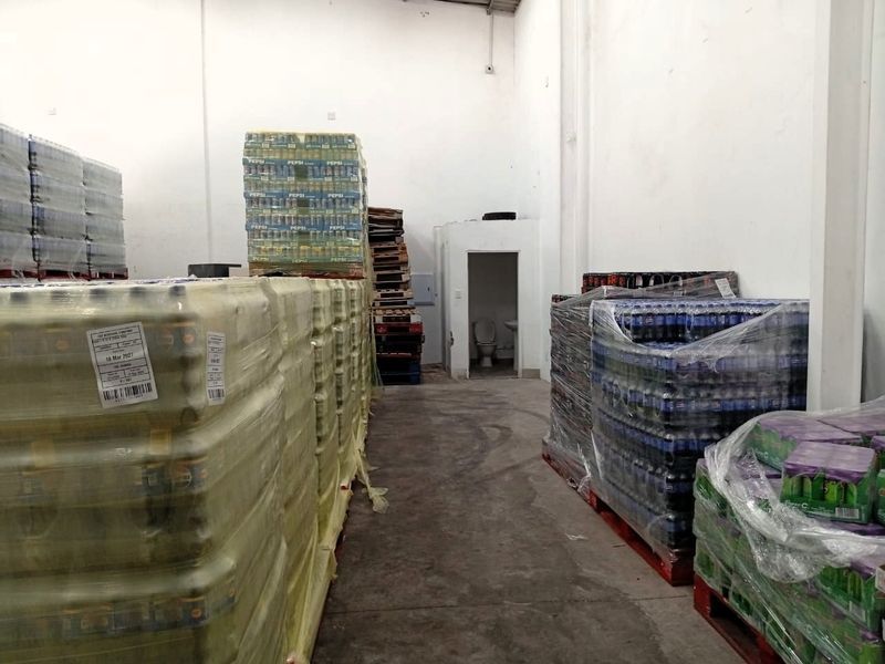 Industrial warehouse storage area featuring high ceilings, concrete flooring, and an integrated restroom facility.