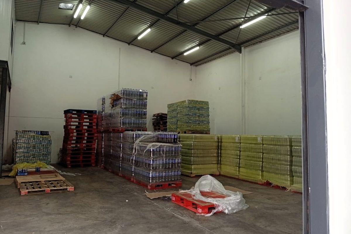 A spacious industrial warehouse unit featuring high-clearance ceilings, exposed steel trusses, durable concrete flooring, and functional overhead fluorescent lighting.
