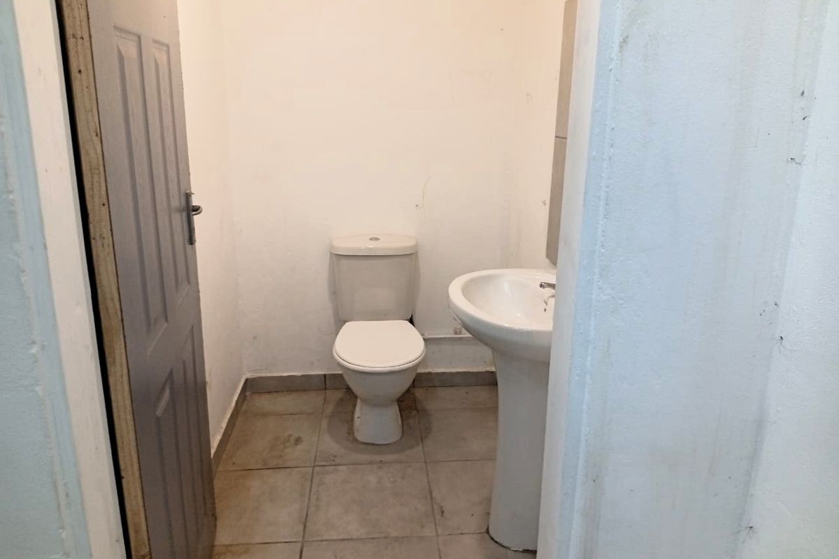 A compact, functional bathroom featuring a standard pedestal basin and toilet with tiled flooring, requiring cosmetic updates to improve its overall condition.