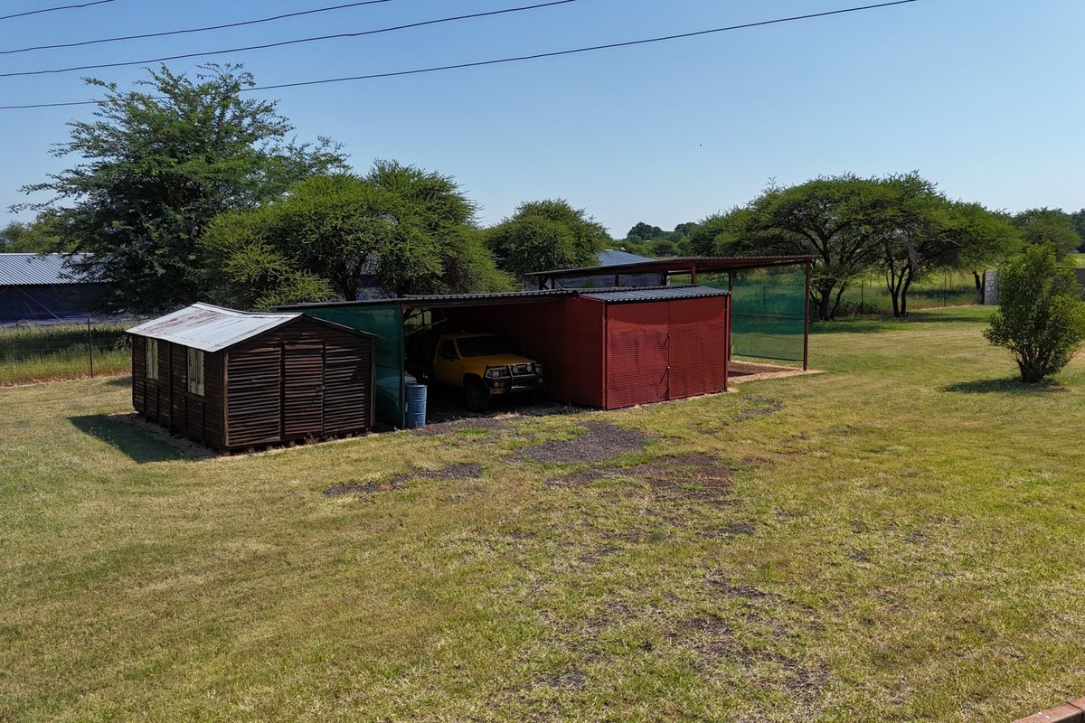 Spacious garden area featuring a metal storage shed and a covered carport structure on the small holding property.