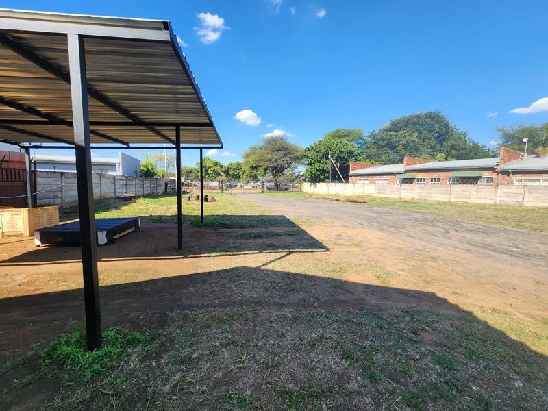 Spacious industrial yard area featuring a metal carport structure and secure precast concrete boundary walls with perimeter fencing.