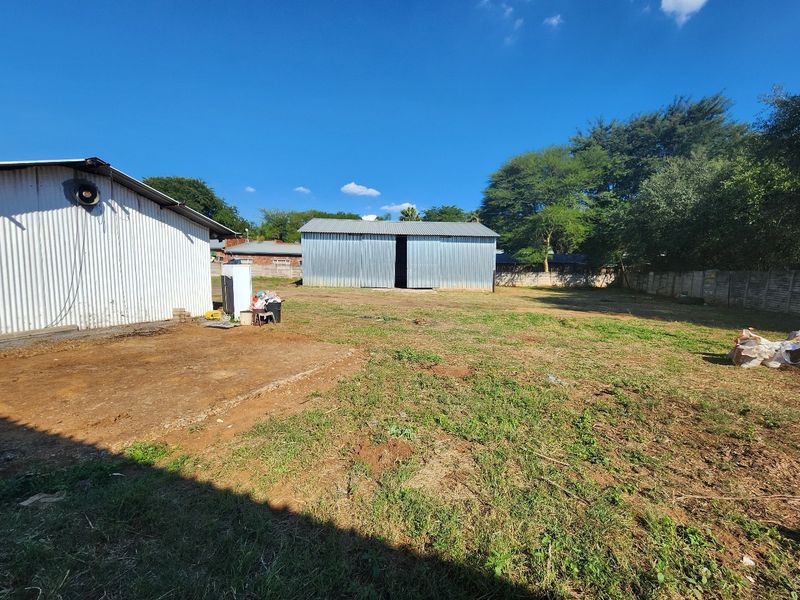 Spacious industrial yard featuring a corrugated metal warehouse structure, secondary shed, and secure precast concrete boundary walling.