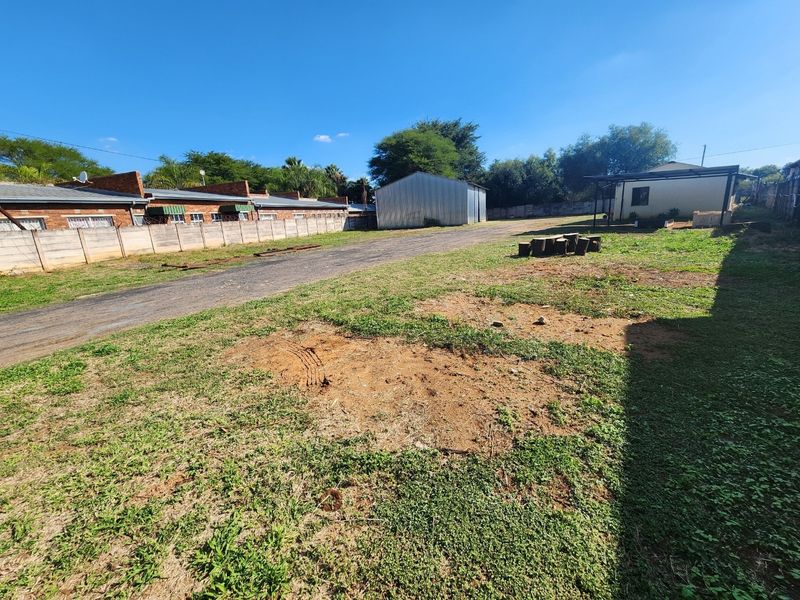 Spacious rear yard featuring a gravel driveway, a metal storage shed, and a precast concrete boundary wall, offering ample outdoor utility space.