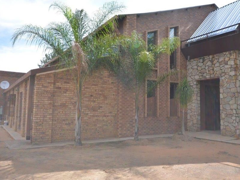Front elevation of a commercial building featuring a combination of face brick and stone cladding with a metal roof.