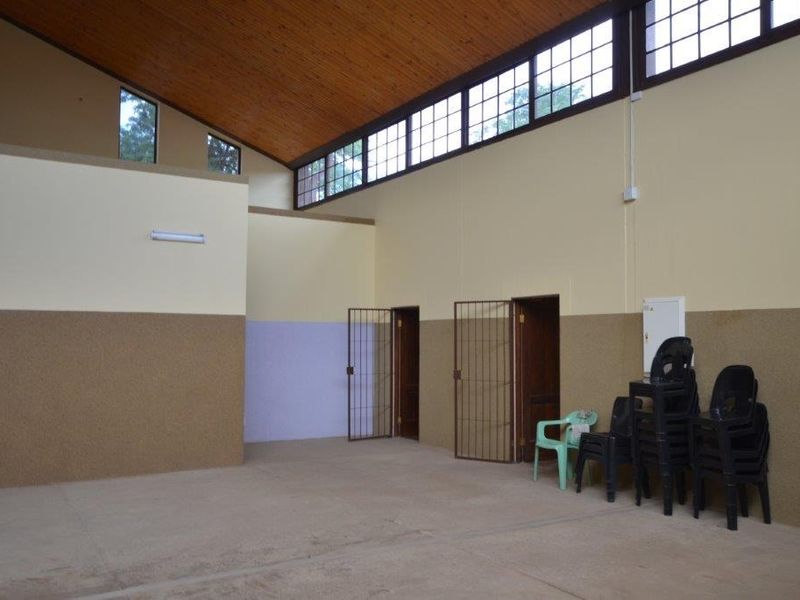Spacious open-plan commercial area featuring high timber raked ceilings, clerestory windows for natural light, and secure access points with metal security gates.