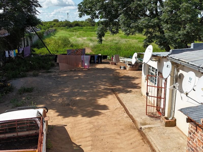 Rear exterior view of the industrial property showing corrugated roofing, multiple satellite dishes, and an unpaved yard area.