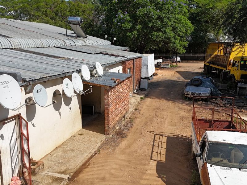 Aerial view of the rear industrial building exterior featuring a corrugated metal roof, solar water heater, and multiple satellite dishes mounted on the wall.