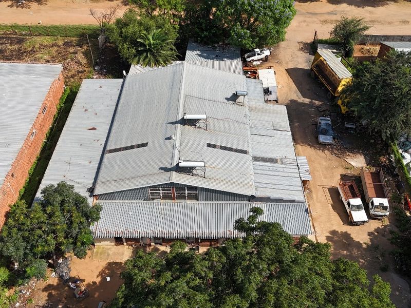 Aerial view of an industrial property featuring a large corrugated metal roof with integrated solar water heating systems and skylights.