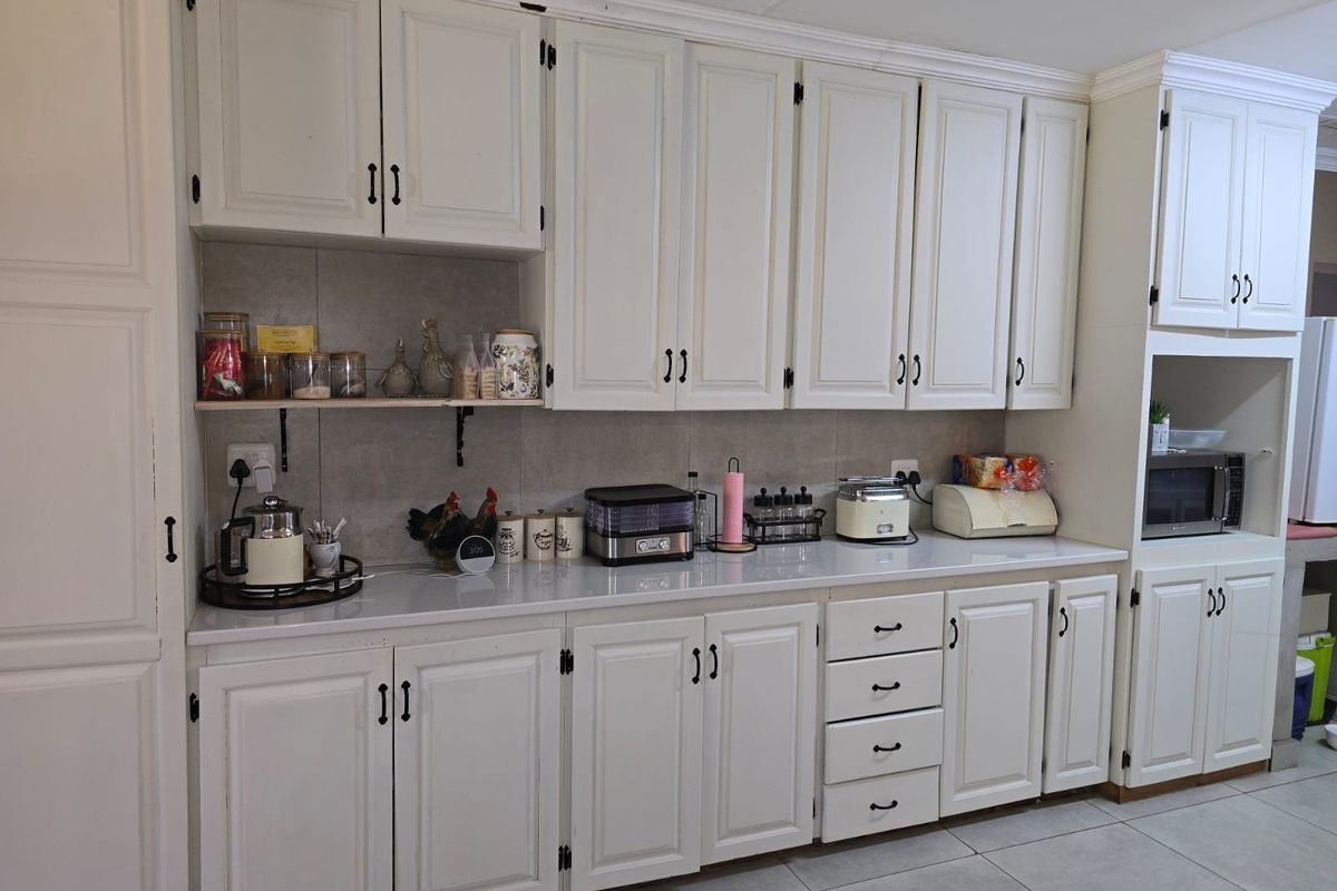 A well-maintained kitchen featuring white shaker-style cabinetry, stone countertops, a tiled backsplash, and integrated microwave housing.