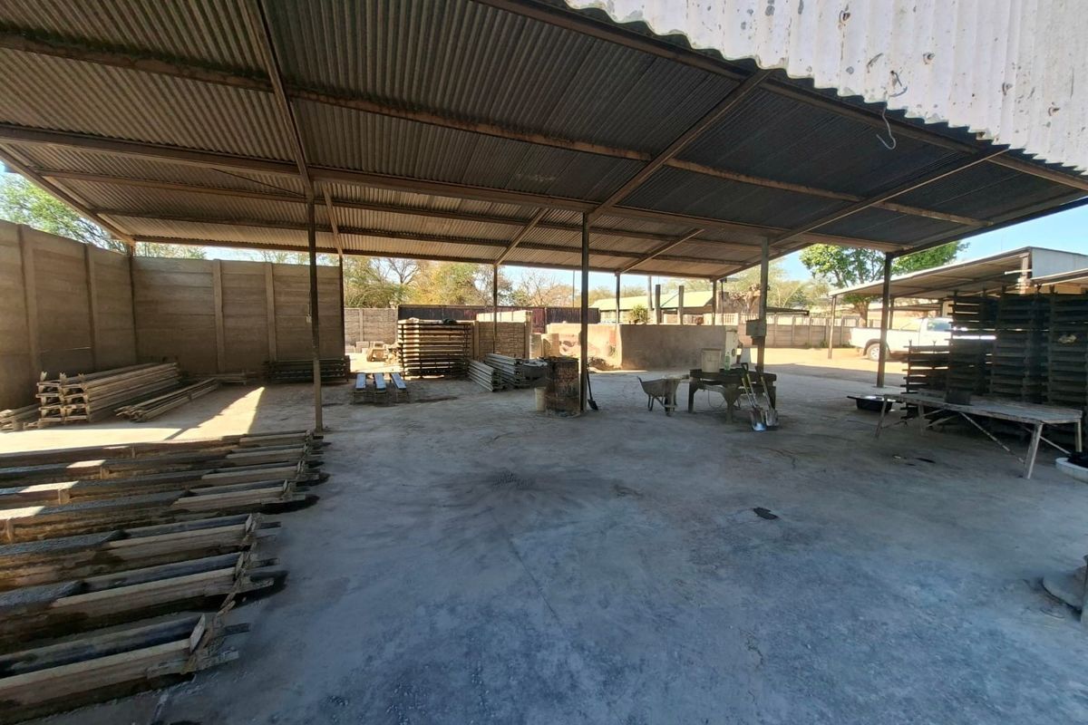 Large industrial utility space featuring a corrugated metal roof structure, steel support columns, and a durable concrete floor, suitable for storage or workshop use.