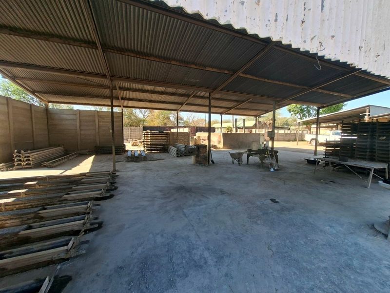 Large industrial utility space featuring a corrugated metal roof structure, steel support columns, and a durable concrete floor, suitable for storage or workshop use.