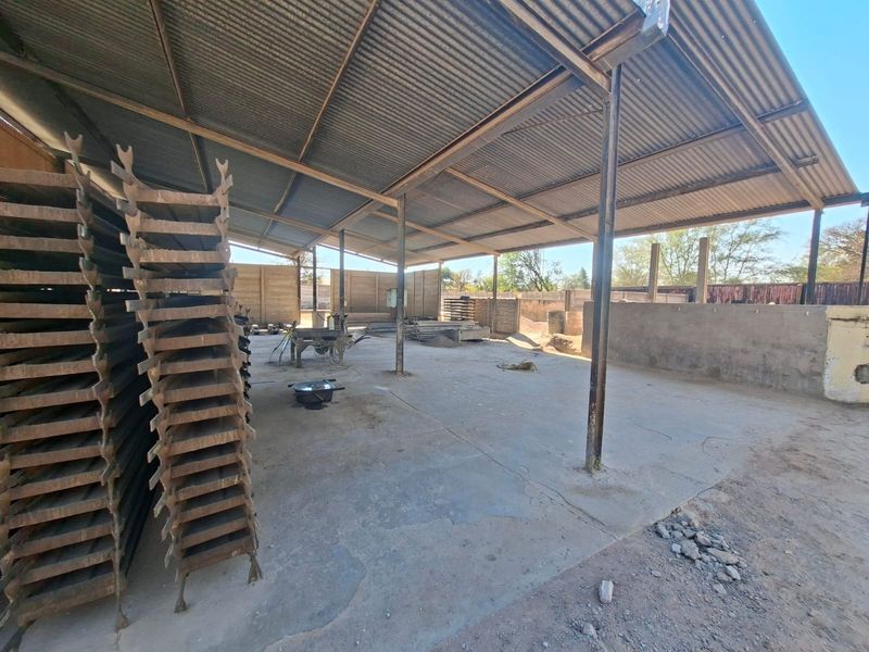 Open-plan industrial utility space featuring a corrugated metal roof, steel support structure, and concrete flooring, suitable for storage or workshop operations.