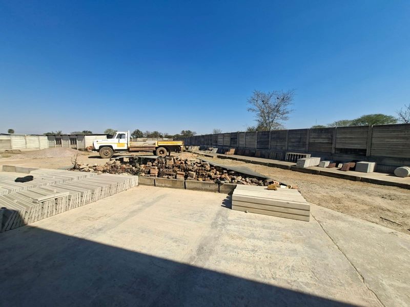 Industrial yard area featuring concrete surfacing and perimeter precast concrete boundary walling, suitable for storage or operational use.