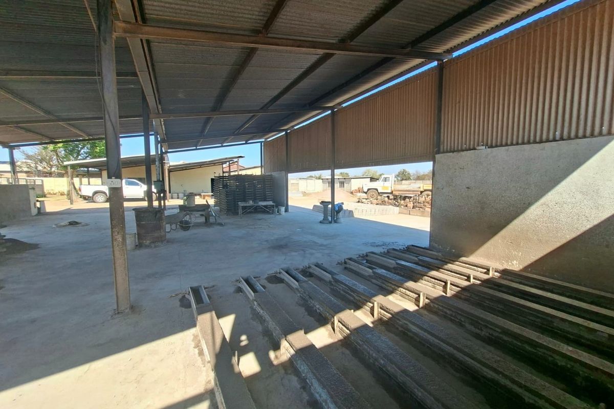 Open-plan industrial utility space featuring a corrugated metal roof, steel support structure, and durable concrete flooring, suitable for manufacturing or storage operations.