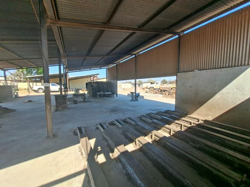 Open-plan industrial utility space featuring a corrugated metal roof, steel support structure, and durable concrete flooring, suitable for manufacturing or storage operations.