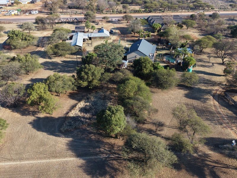 Aerial view of a lodge property featuring multiple buildings, a swimming pool, and extensive surrounding grounds with natural vegetation.