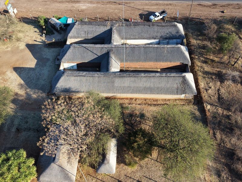 Aerial view of a lodge property featuring multiple connected structures with traditional thatch roofing and brick exterior walls set within a rural landscape.