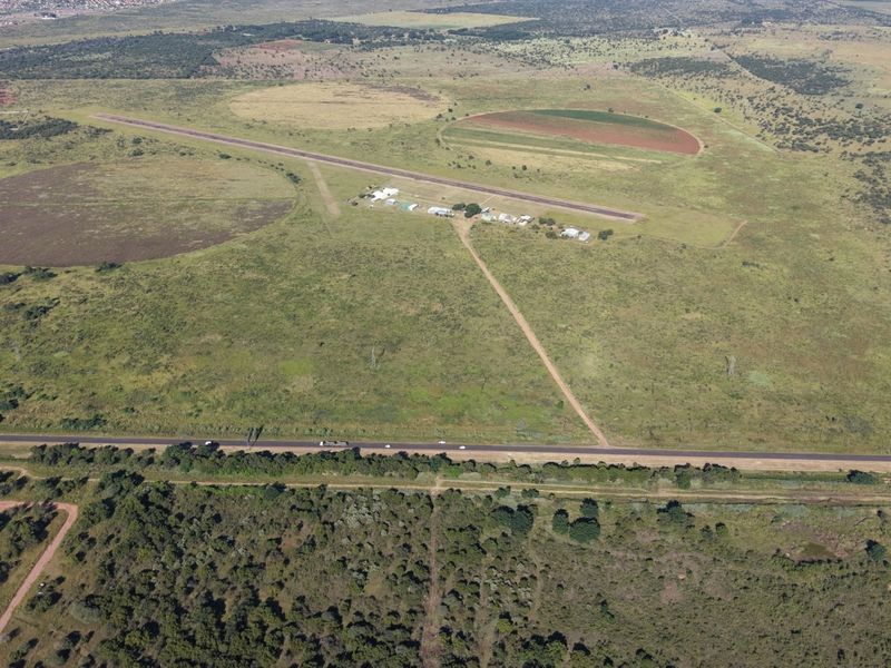 Aerial view of a large commercial vacant land plot featuring an existing airstrip, access road, and surrounding natural landscape.