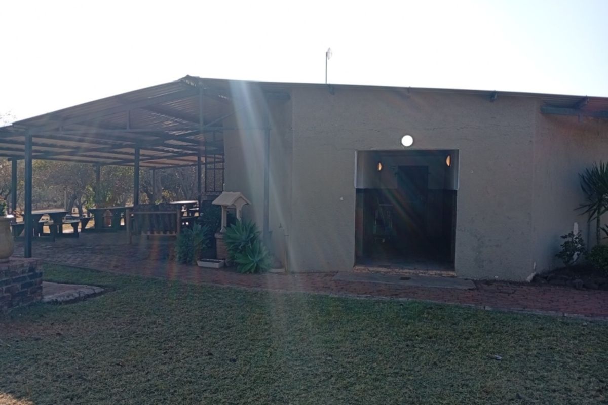 Rear view of the property featuring a large covered patio area with brick paving and direct access to the garden.