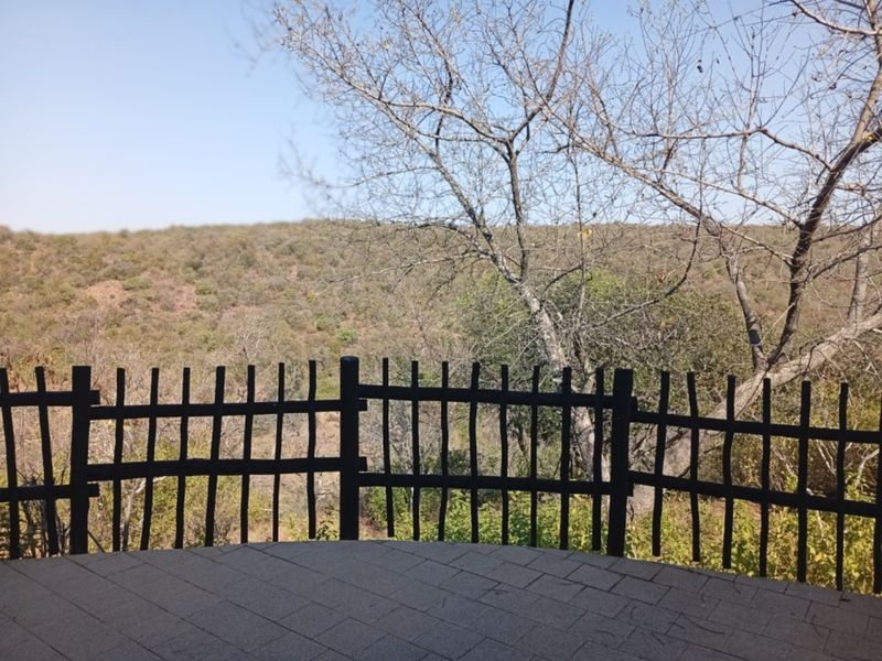 An outdoor patio area featuring paved flooring and a timber fence, offering scenic views of the surrounding natural landscape.