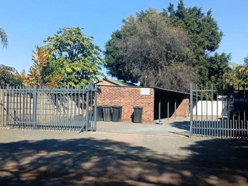 A view of a brick-built carport area secured by metal gates, providing covered parking space.
