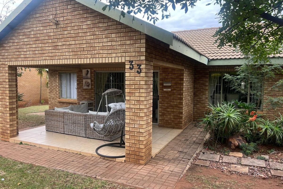A covered brick patio area featuring tiled flooring and sliding glass door access to the main house interior.