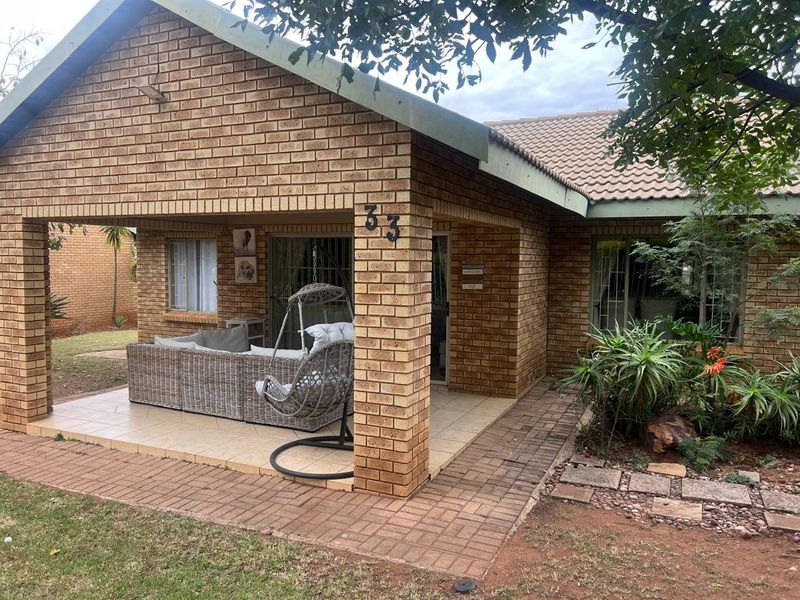 A covered brick patio area featuring tiled flooring and sliding glass door access to the main house interior.