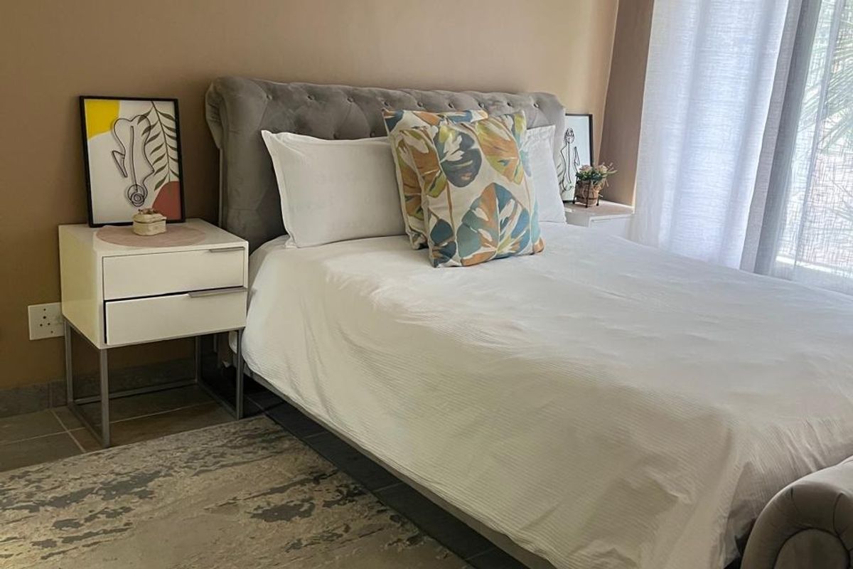 A well-maintained bedroom featuring tiled flooring, a ceiling fan, and a sliding glass door providing natural light.