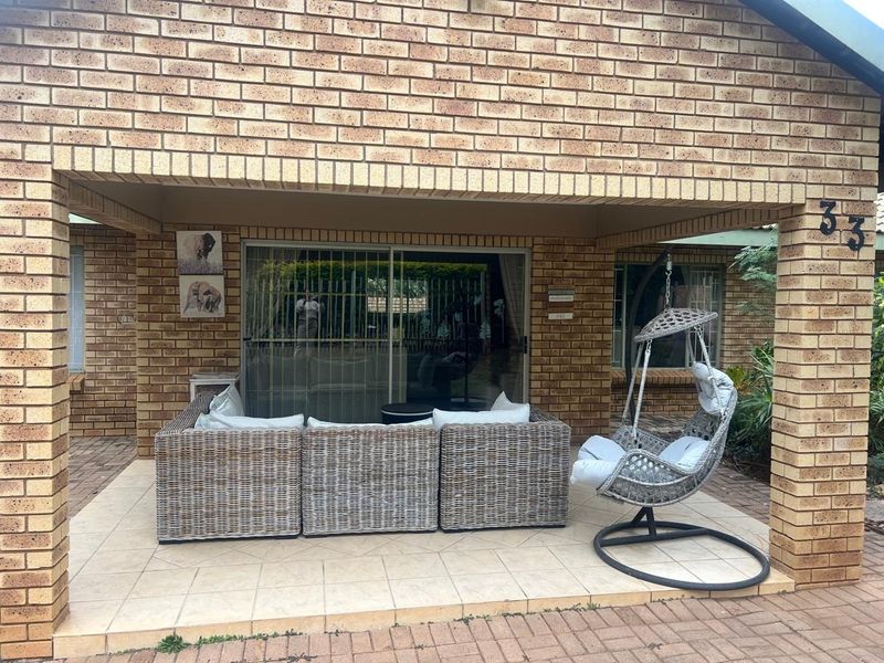 A covered patio area featuring face brick construction and tiled flooring, providing direct access to the interior through a sliding glass door.