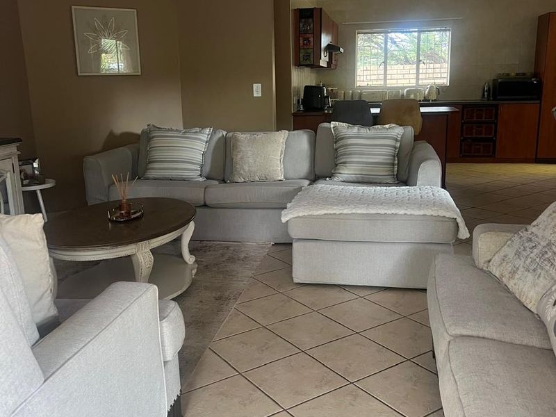 Open plan living area featuring tiled flooring, a ceiling fan, and a connected kitchen space with wooden cabinetry.
