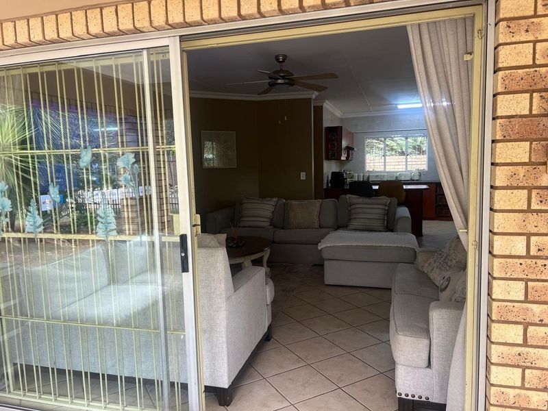 Open-plan living area featuring tiled floors, a ceiling fan, and direct access to the outdoor patio through a sliding glass door.