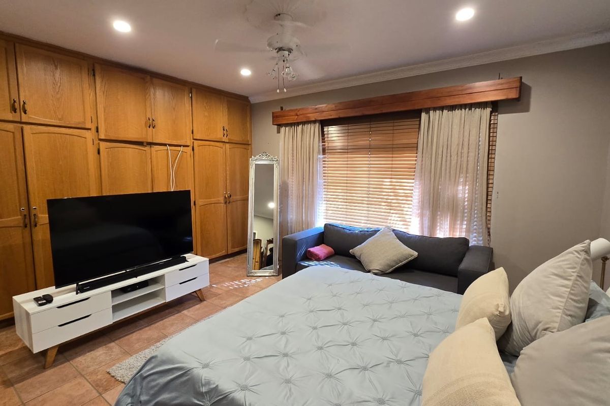 Spacious bedroom featuring extensive built-in wooden cabinetry, tiled flooring, recessed lighting, and a ceiling fan, offering ample storage and a comfortable layout.