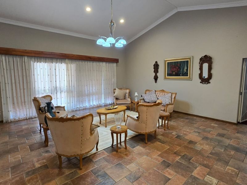 Spacious living room featuring vaulted ceilings, tiled flooring, and large sliding glass doors with a timber pelmet, offering a bright and open atmosphere.
