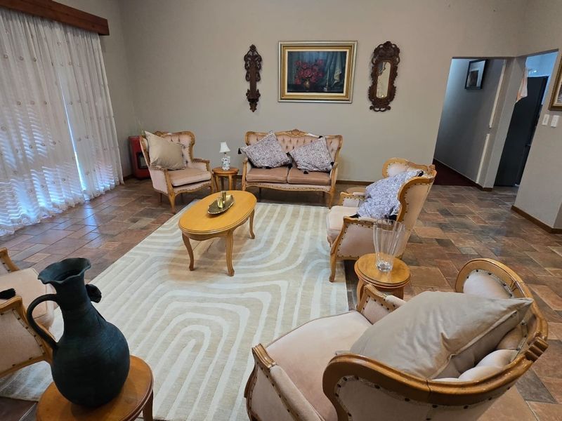 Spacious living room featuring terracotta floor tiles and a large sliding glass door with a wooden pelmet, offering a traditional aesthetic.