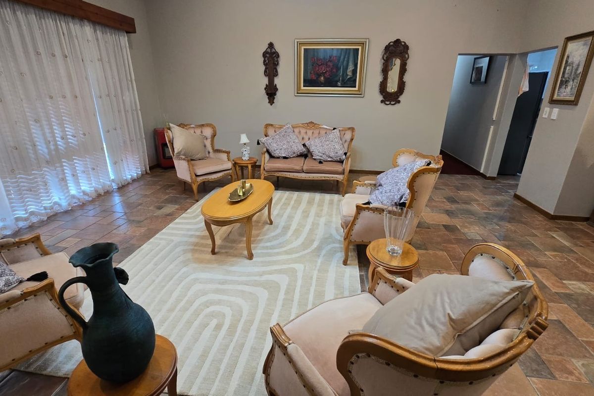 Spacious living room featuring terracotta floor tiles and a large sliding glass door with a wooden pelmet, offering a traditional aesthetic.
