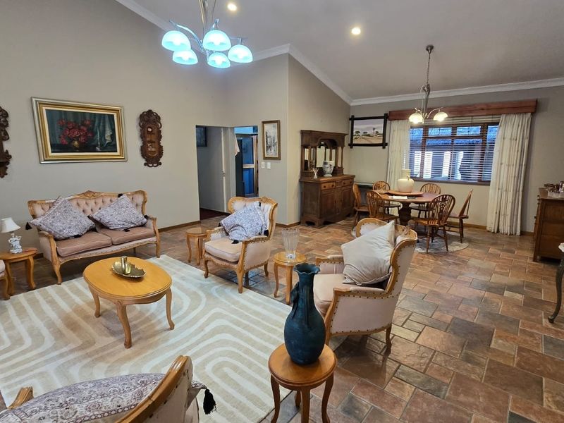 Spacious open-plan living and dining area featuring vaulted ceilings, tiled flooring, and recessed lighting, offering a versatile layout for comfortable family living.