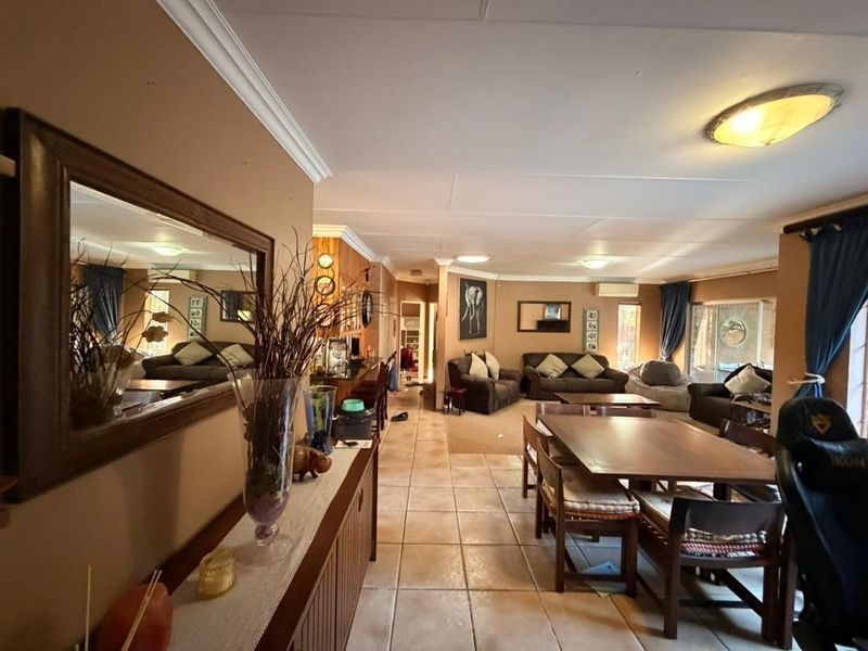 Spacious open-plan living and dining area featuring tiled flooring, neutral wall tones, and direct access to outdoor space through sliding glass doors.