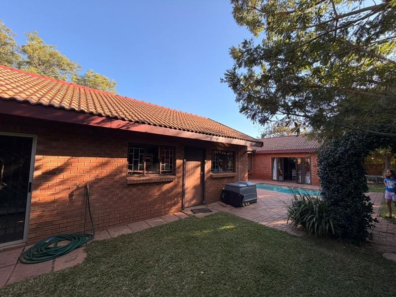 Rear view of the townhouse featuring a brick facade, tiled roof, paved patio area, and a private swimming pool.