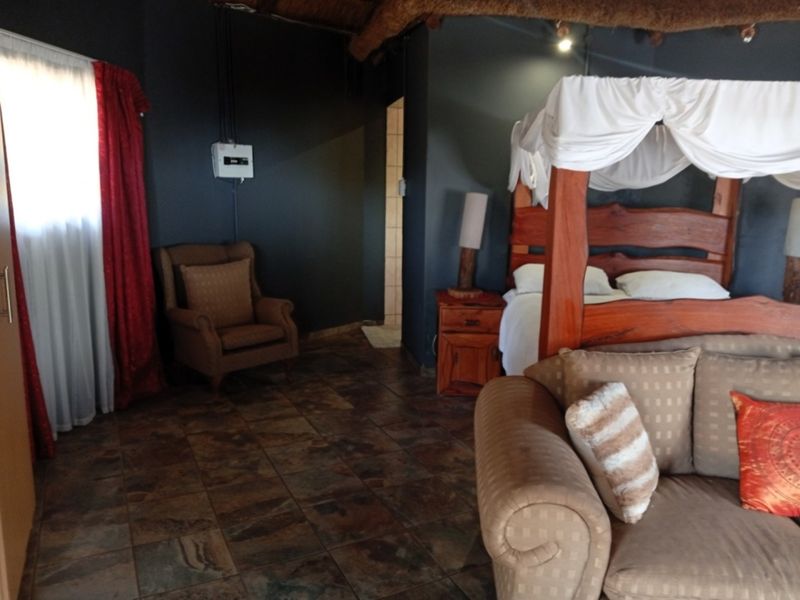 A bedroom featuring dark walls, tiled flooring, and a traditional thatched ceiling, offering a rustic aesthetic with potential for modern interior updates.