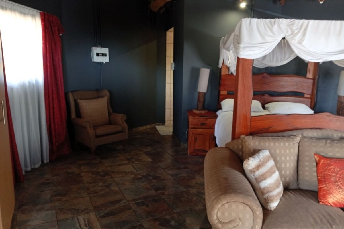 A bedroom featuring dark walls, tiled flooring, and a traditional thatched ceiling, offering a rustic aesthetic with potential for modern interior updates.