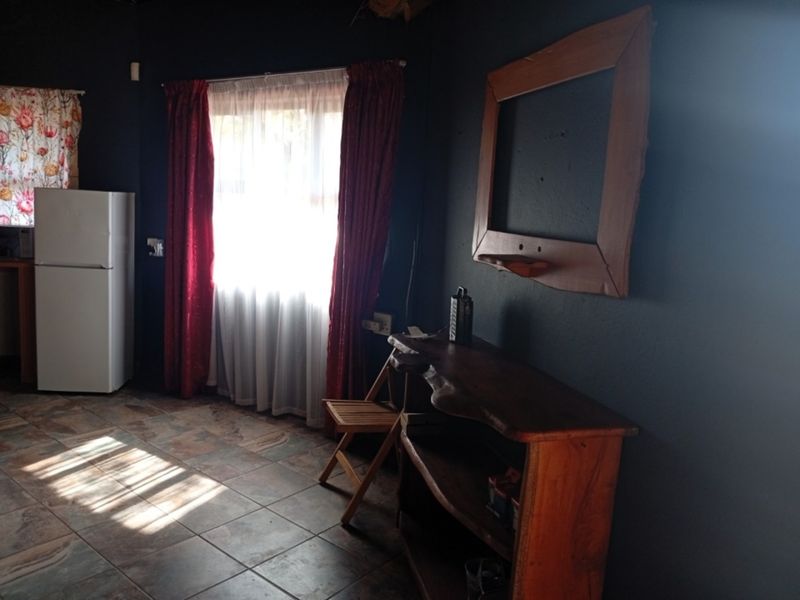 A living area featuring dark painted walls, tiled flooring, and a window with curtains, providing a functional space with potential for modernization.