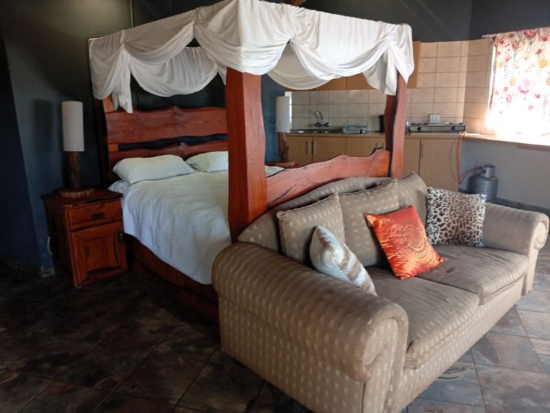 Open-plan studio apartment featuring a combined sleeping and kitchen area with tiled flooring and built-in cabinetry.