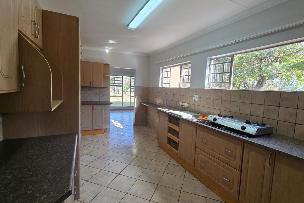 A functional kitchen featuring built-in wooden cabinetry, laminate countertops, a gas hob, and neutral ceramic tiling throughout.